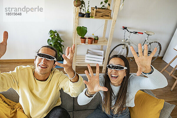 Cheerful couple wearing smart glasses gesturing at home
