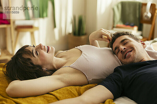 Lächelnder Freund und Frau entspannen sich zu Hause im Bett