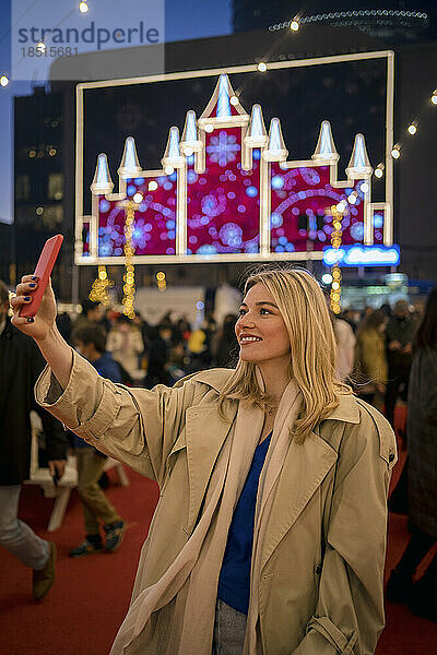 Lächelnde Frau  die beim Festival ein Selfie mit ihrem Smartphone macht