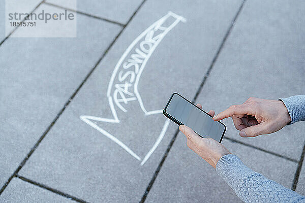 Mann benutzt Smartphone mit Textpfeil auf Fußweg