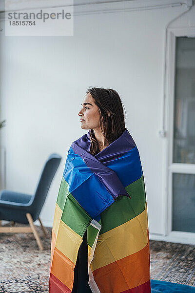 Junge Geschäftsfrau in Regenbogenfahne gehüllt