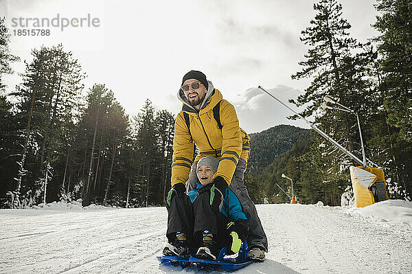 Glücklicher Vater und Sohn genießen das Rodeln im Schnee