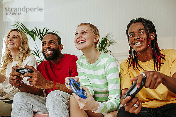 Junge Männer und Frauen spielen mit Freunden zu Hause Videospiel