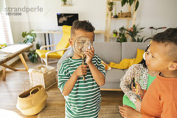 Boy looking through magnifying glass at home
