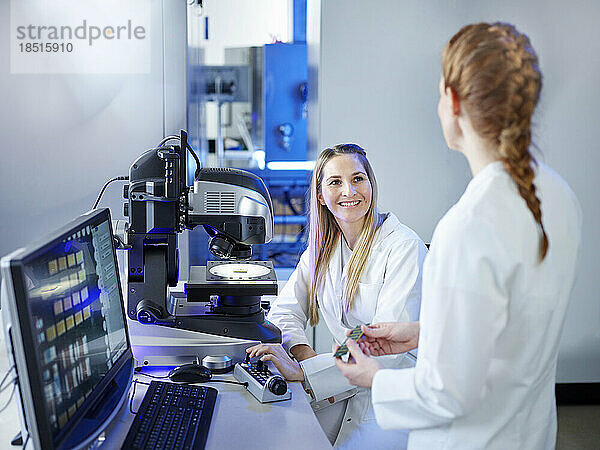 Lächelnder Wissenschaftler diskutiert mit Techniker im E-Labor