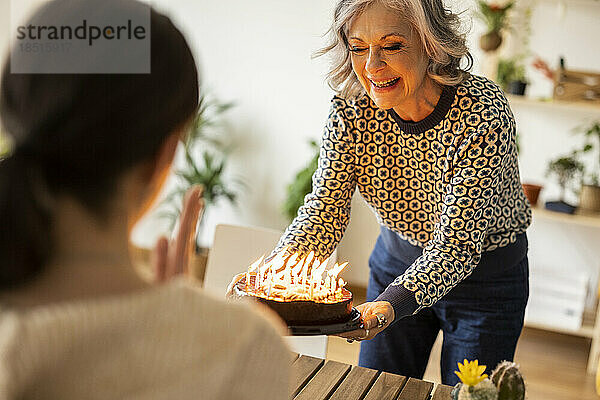 Lächelnde reife Frau feiert zu Hause den Geburtstag ihrer Tochter