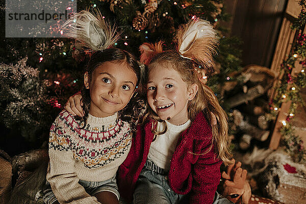 Nachdenklich lächelnde Schwestern sitzen zu Weihnachten zusammen