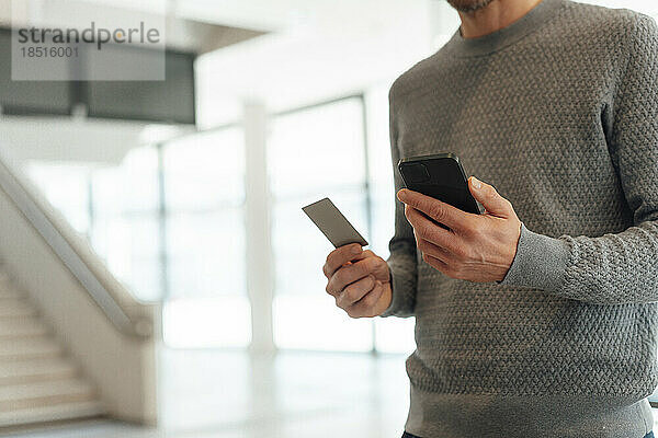 Mann hält Kreditkarte und Smartphone in der Hand