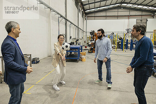 Glückliche Ingenieure spielen Volleyball mit Fußball in der Industrie