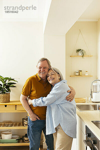 Zärtliches Seniorenpaar umarmt sich in der Küche