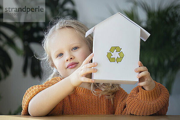 Mädchen hält Hausmodell mit Recycling-Logo