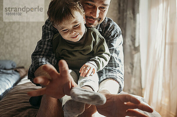 Lächelnder Vater trägt Socken an den Füßen seines Sohnes