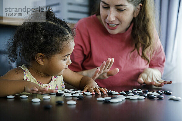 Mutter spielt Go-Spiel mit Tochter zu Hause am Tisch