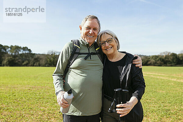 Lächelnder älterer Mann mit Arm um Frau  die auf grüner Landschaft steht