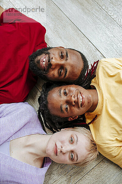 Smiling young multiracial friends lying on floor at home