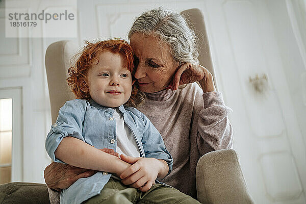 Großmutter und Enkel sitzen zu Hause im Sessel