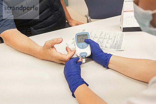 Arzt überprüft Blutzuckerspiegel des Patienten in der Klinik