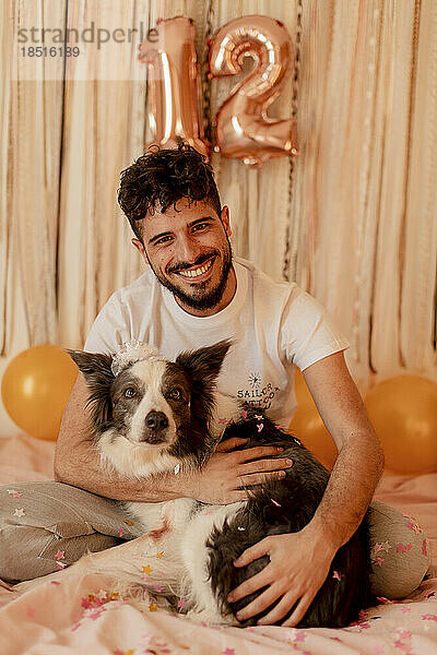 Happy young man celebrating border collie dog's birthday