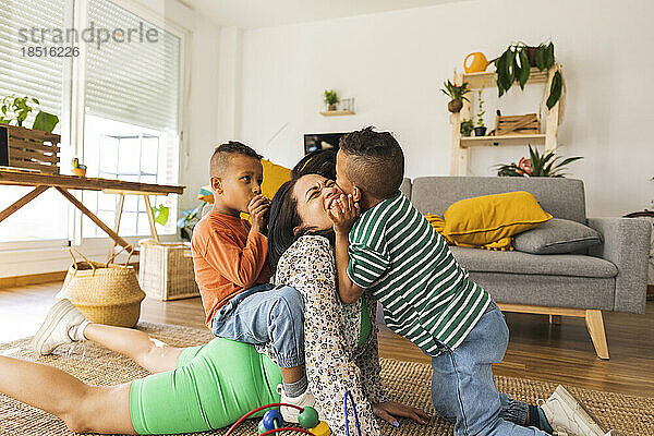 Boys playing with mother in living room at home