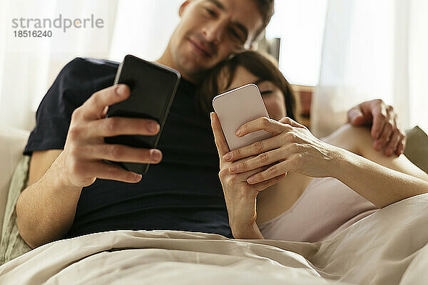Paar benutzt Smartphones im Schlafzimmer