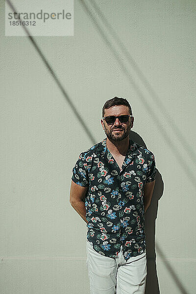 Man wearing sunglasses standing in front of wall