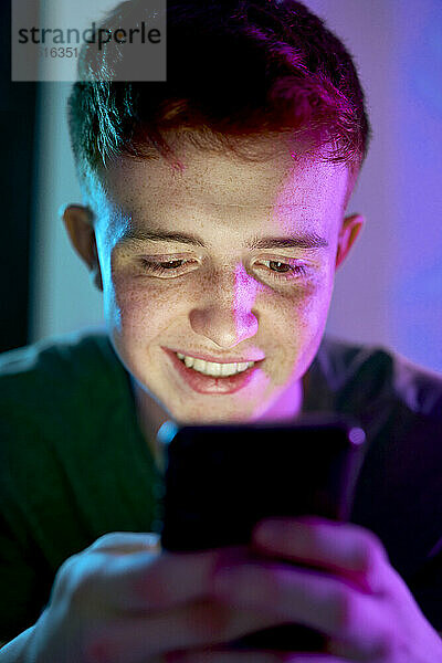 Glücklicher junger Mann  der mit dem Smartphone im Internet surft