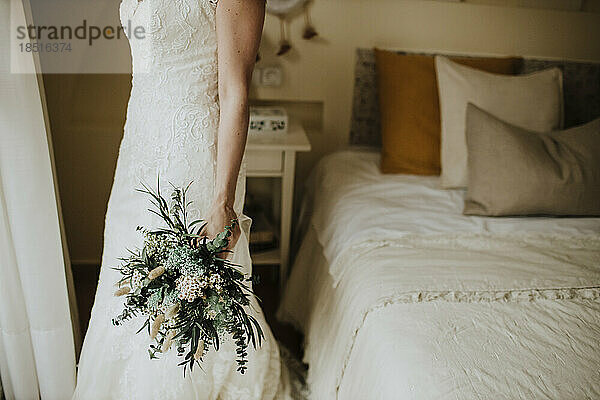 Braut hält Blumenstrauß im Schlafzimmer