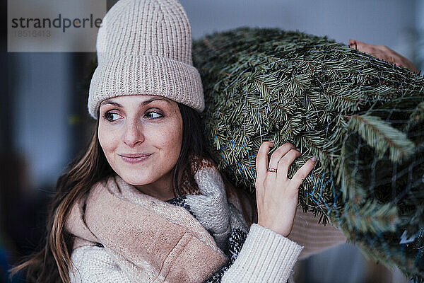 Lächelnde junge Frau mit Weihnachtsbaum