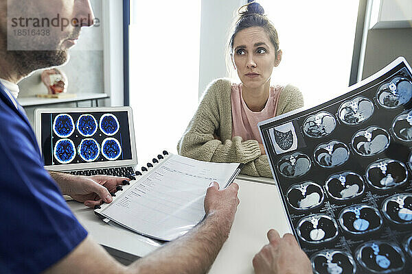 Ärzte diskutieren mit Patienten in der Klinik über medizinische Röntgenbilder