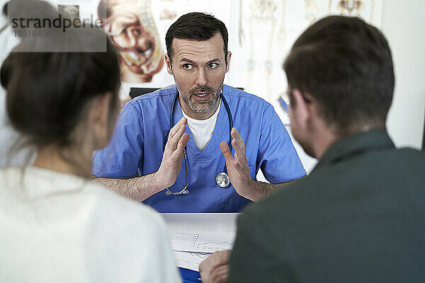 Doctor explaining and having discussion with couple in clinic