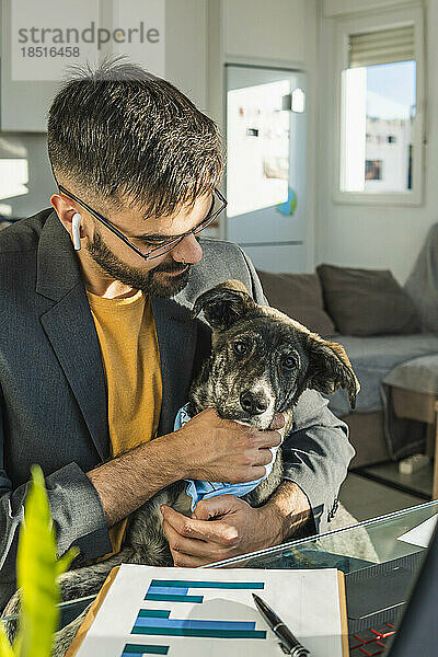 Geschäftsmann streichelt Hund im Heimbüro