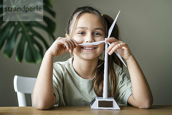 Lächelndes Mädchen mit Windturbinenmodell zu Hause