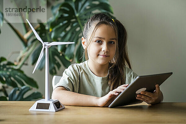 Mädchen mit Tablet-PC von Windturbinenmodell auf dem heimischen Tisch