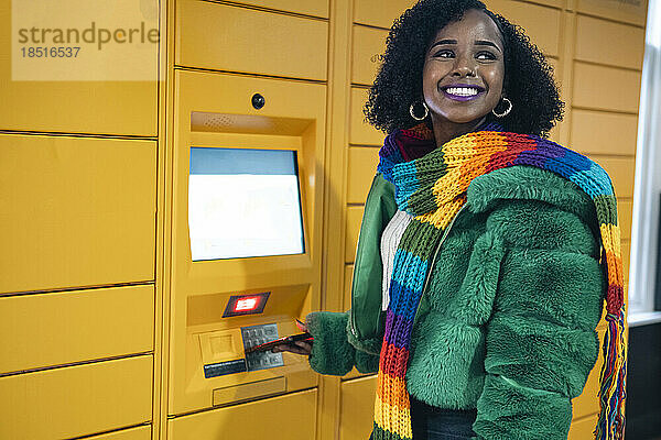 Glückliche Frau  die in der Nähe eines Fahrkartenautomaten steht
