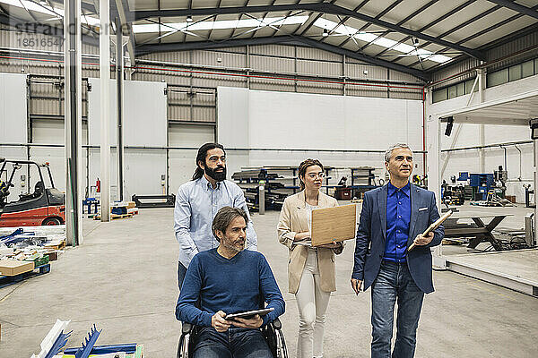 Behinderter Ingenieur diskutiert mit Kollegen in der Fabrik