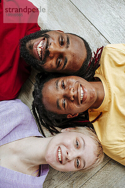 Happy multiracial friends lying on floor at home