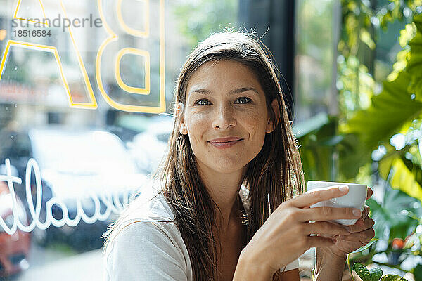 Lächelnde Frau mit Kaffeetasse im Café