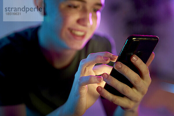 Lächelnder junger Mann  der Smartphone benutzt