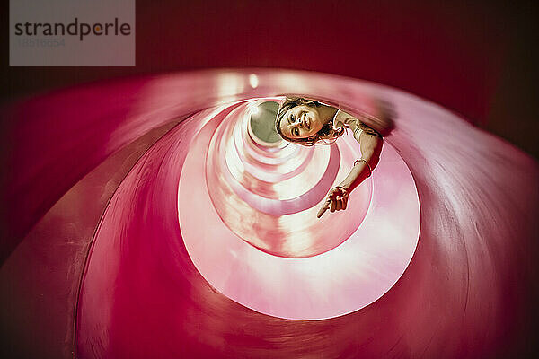 Smiling woman gesturing inside spiral structure