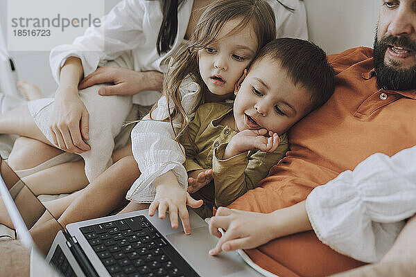 Glückliche Familie  die gemeinsam zu Hause Laptop benutzt