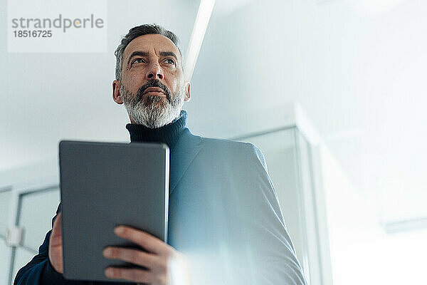 Reifer Geschäftsmann hält Tablet-PC im Büro