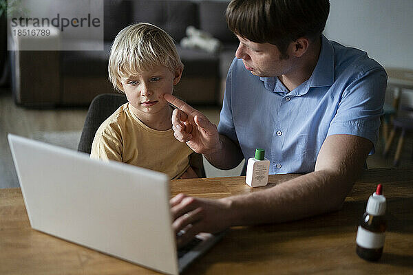 Vater zeigt dem Arzt zu Hause am Laptop die Windpocken seines Sohnes