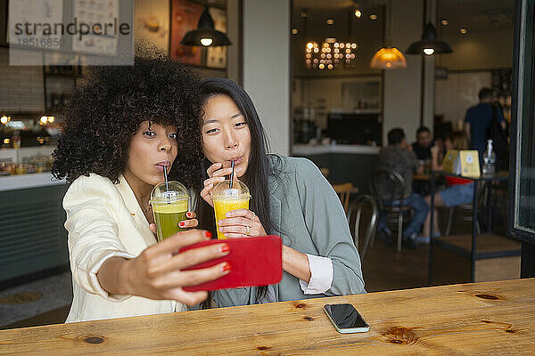 Freunde machen Selfie und trinken gesunden Saft im Café
