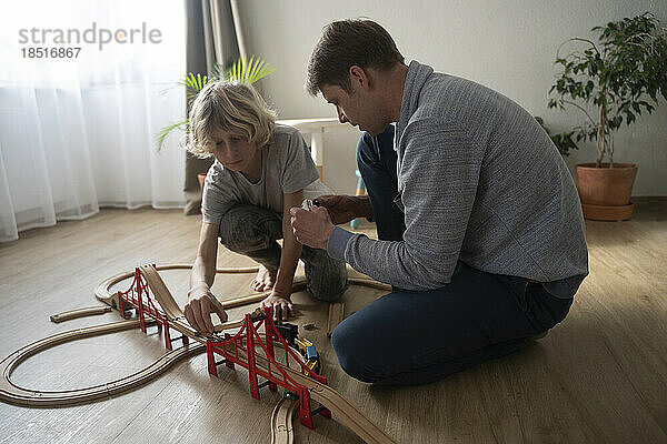Father and son playing together with toy train at home