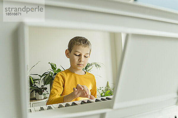 Boy playing electric piano at home