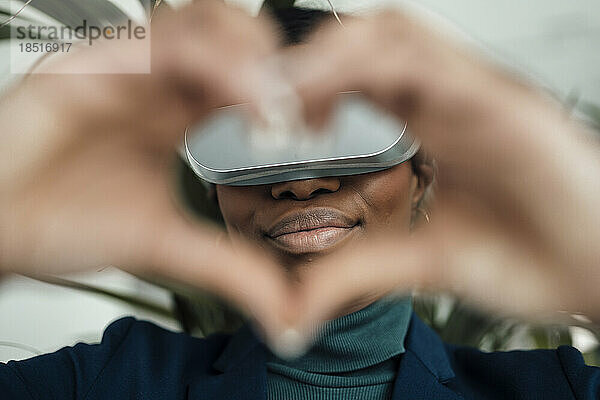 Frau mit Virtual-Reality-Headset macht eine Herzgeste