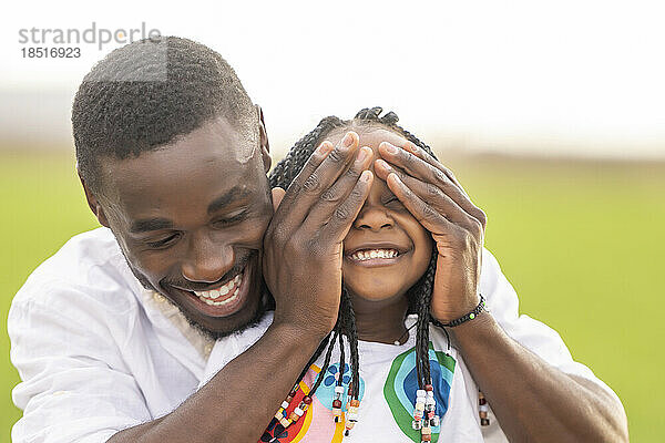 Glücklicher Vater bedeckt die Augen seiner Tochter und hat Spaß