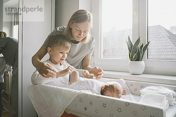 Frau und Junge kümmern sich um das Baby  das zu Hause auf dem Wickeltisch schläft
