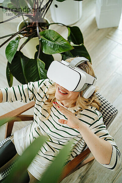Happy woman with prosthetic legs wearing VR glasses sitting at home