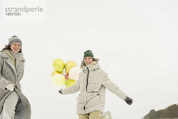 Glückliche Frauen  die Luftballons halten und den Winter genießen